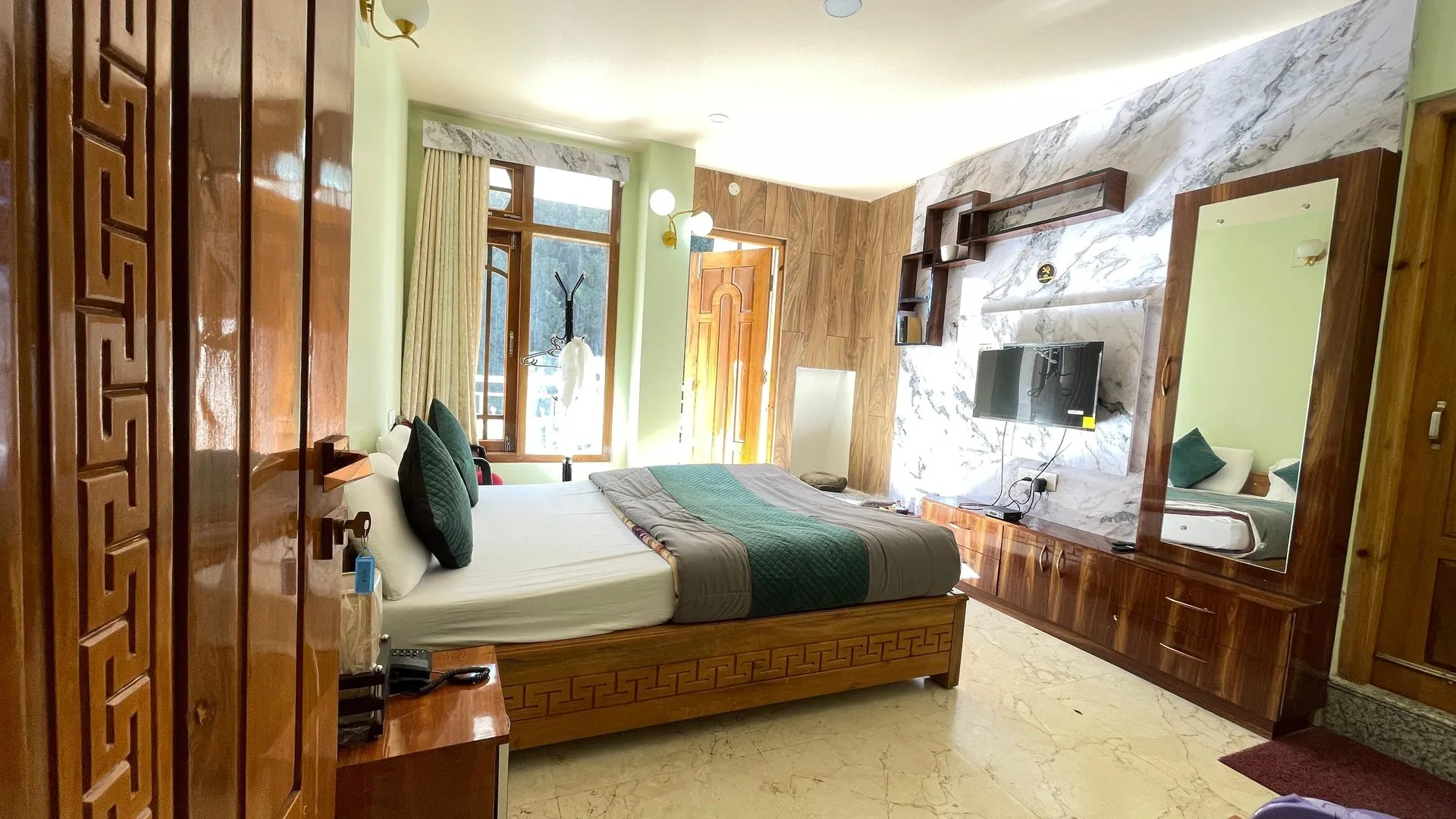 Deluxe Room showing the bed, television, window and wooden decor
